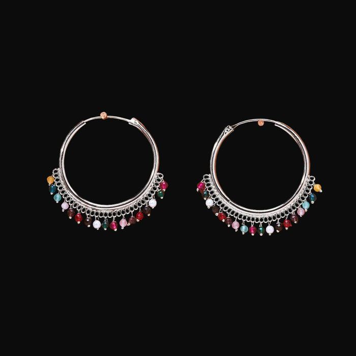 Pair of silver hoop earrings with colorful beads on a brown background