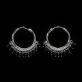 Pair of silver hoop earrings with black beads on a brown textured background