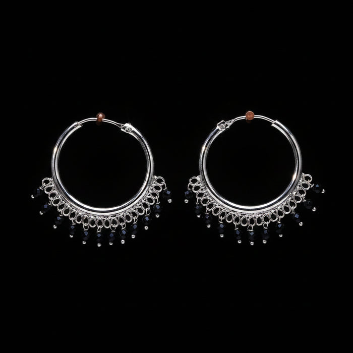 Pair of silver hoop earrings with black beads on a brown textured background