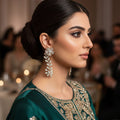Pair of floral diamond earrings on a dark background with 'SAHELI' branding.