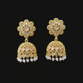 Gold earrings with floral design on a gray stand against a black background