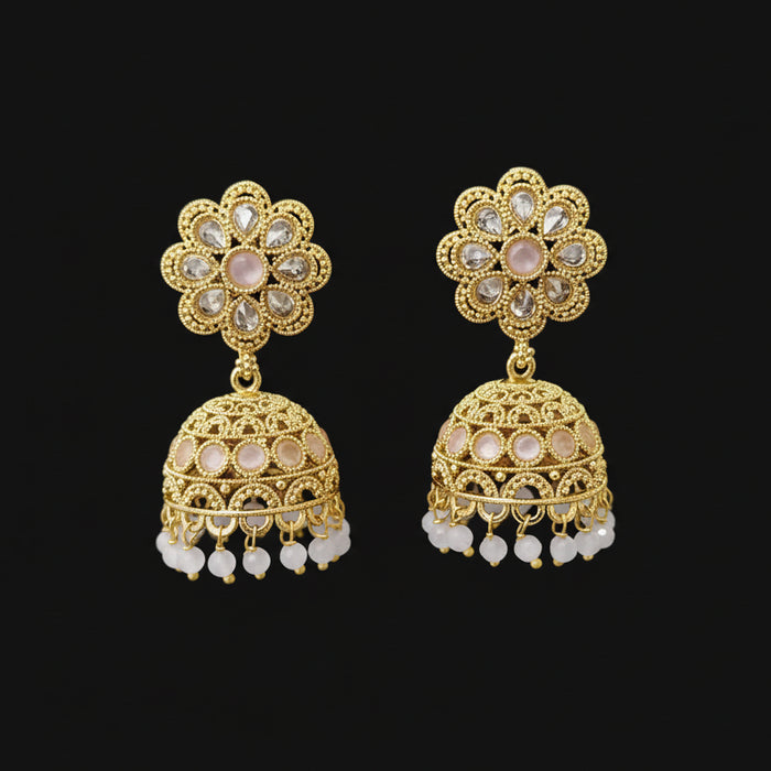 Gold earrings with floral design on a gray stand against a black background