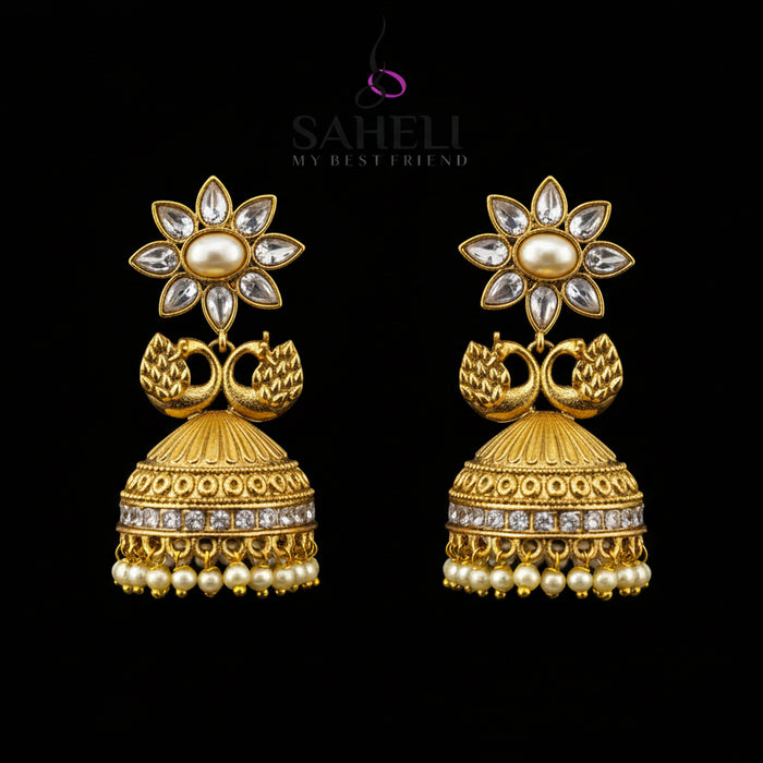 Gold earrings with floral design on a gray stand, branded 'Sahello'.