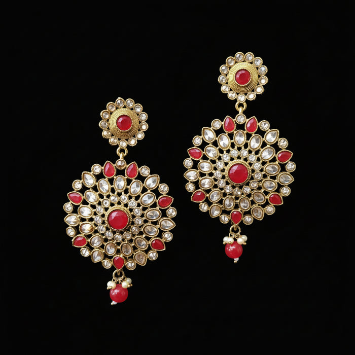 Gold and red earrings on a gray stand with 'Saheli' branding.