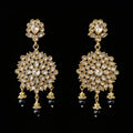 Gold and black earrings on a gray stand with 'SAHELI' branding.