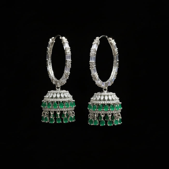 Pair of silver and green earrings on a gray stand with 'Saheli' branding.