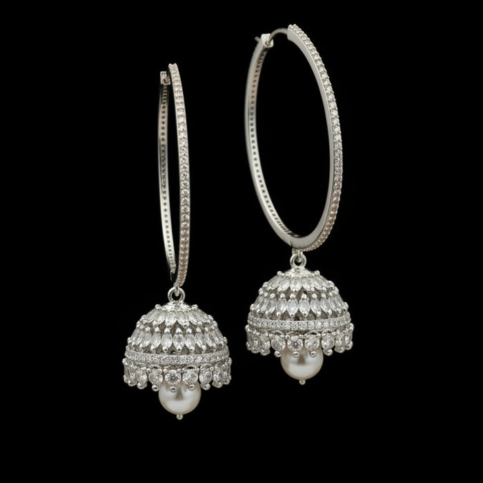 Gold hoop earrings with spherical embellishments on a black stand against a dark background.
