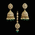 Gold and green earrings on a gray stand with 'Saheli' branding.