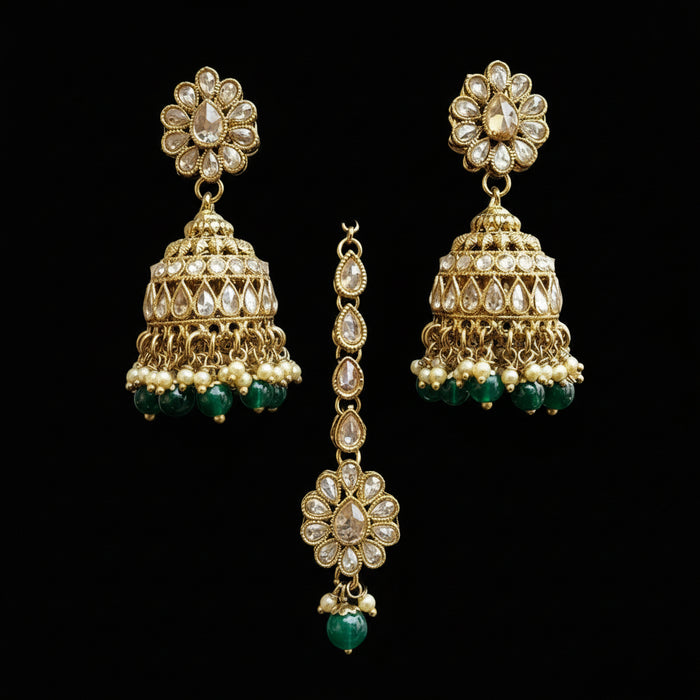 Gold and green earrings on a gray stand with 'Saheli' branding.