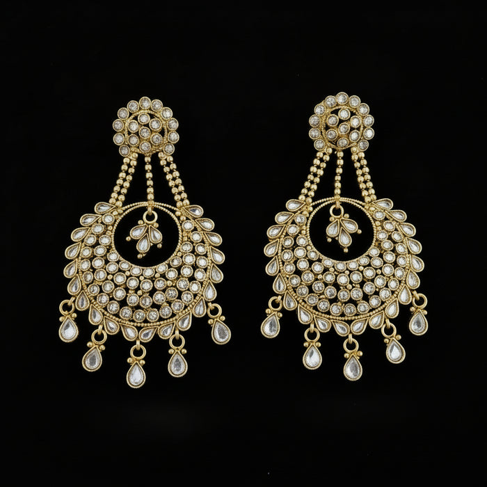 A pair of gold-toned traditional Indian chandelier earrings embellished with clear stones, displayed on a dark reflective surface with the brand name 'SAHELI MY BEST FRIEND' printed above.