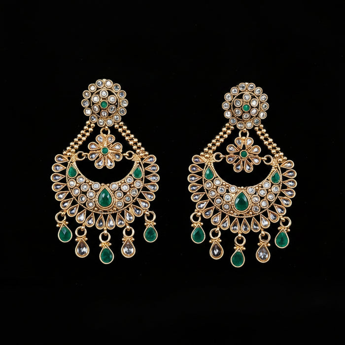 A pair of gold-toned Indian chandelier earrings with green stone accents and clear crystal-like stones, displayed on a black background with the brand logo 'SAHELI MY BEST FRIEND' at the top.