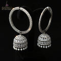 Silver hoop earrings with spherical embellishments on a dark stand against a gray background.