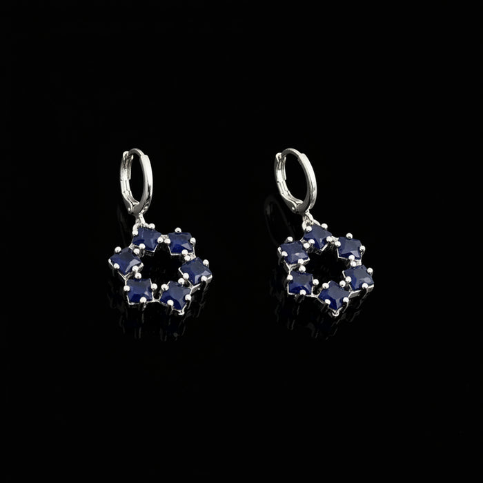 Pair of silver earrings with blue gemstones on a gray background, featuring the brand 'Saheli'.