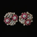 Pair of floral earrings with red and silver stones on a dark background, branded 'Saheli'.