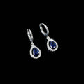 Pair of silver earrings with blue gemstones on a black background