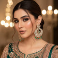 Ornate earrings with green gemstones on a black background, branded 'Saheli'.