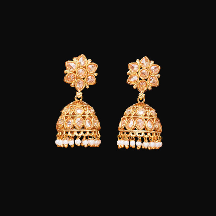 Gold earrings with floral top and bell-shaped bottom on a brown background
