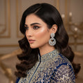 Pair of diamond earrings on a dark gray stand