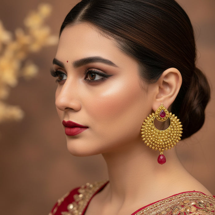 Gold earrings with red gemstones on a dark background