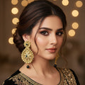 Gold earrings with black stones on a dark background, branded 'SAHELI'.
