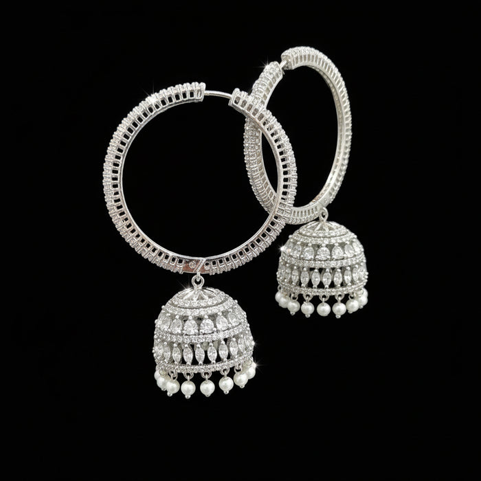 Silver earrings held by a hand with a blurred background