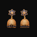 Gold and blue floral earrings on a brown background