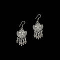 Pair of silver earrings with intricate designs on a gray background, branded 'Saheli'.