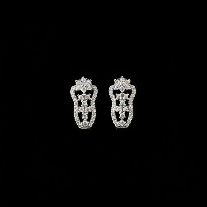 Silver earrings on a black stand with 'Saheli' branding on a dark background