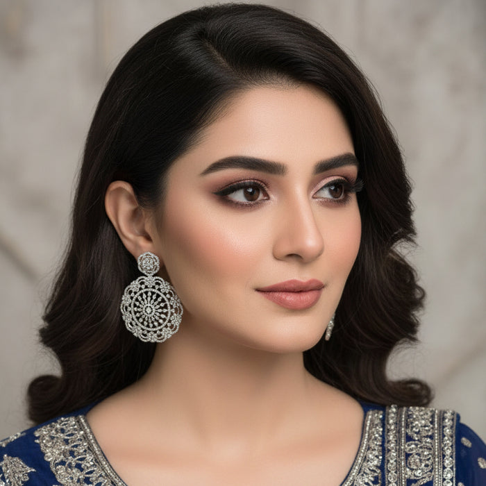 Pair of silver earrings with intricate designs on a black background