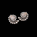A pair of ornate pearl and rose gold earrings with a floral or fan-like design, displayed on a dark reflective surface.