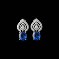 Pair of silver earrings with blue stones on a gray background, branded 'Saheli'.
