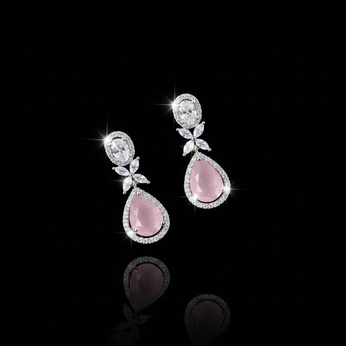 Pair of earrings with pink teardrop stones and silver accents on a dark background