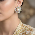 Pair of gold and pearl earrings on a dark background