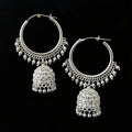 Silver hoop earrings with jhumka designs on a black background, featuring the brand 'Saheli'.