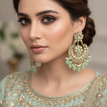 Ornate gold and green earrings on a dark background