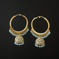 Gold hoop earrings with blue gemstones on a gray stand against a dark background