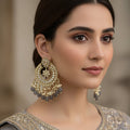 Ornate gold and black earrings with 'SAHELI' branding on a dark background