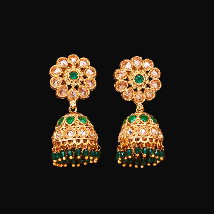 Gold and green floral earrings on a brown background