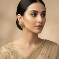 Pair of gold and pearl earrings on a dark gray background