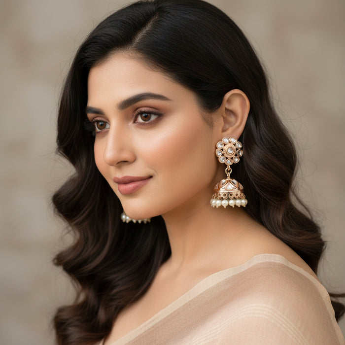 Gold and pearl earrings on a gray stand with 'SAHELI' branding.