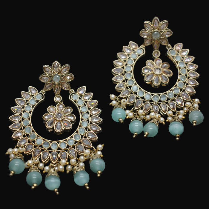 Ornate earrings with floral designs and turquoise beads on a dark background