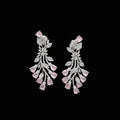 A pair of silver-toned dangle earrings decorated with pavé-set clear stones and pink teardrop gemstones, displayed on a dark gray background.