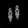 A pair of ornate silver-toned dangle earrings embellished with clear pavé stones and accented with purple amethyst teardrop and round stones, displayed on a dark gray background.
