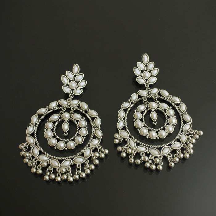 Pair of silver earrings with intricate designs on a black background