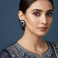 Pair of earrings with dark gemstones and clear stones on a red background