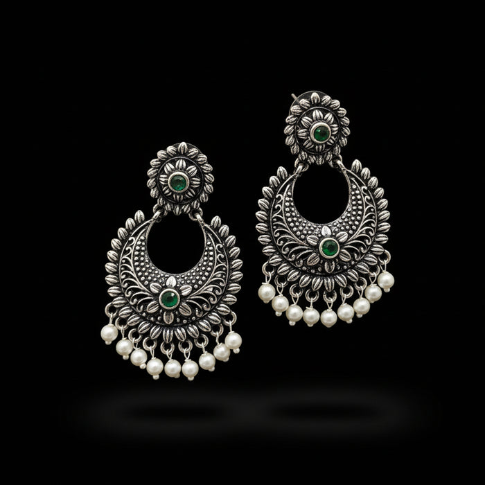 Pair of silver earrings with green stones and pearl-like beads on a gray background, branded 'Saheeli'.