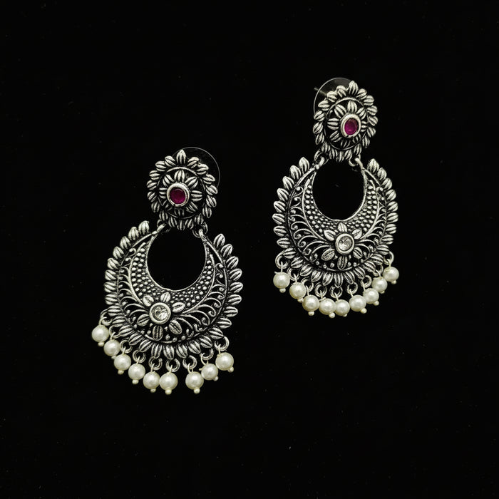 Pair of silver earrings with pearls and gemstones on a black background