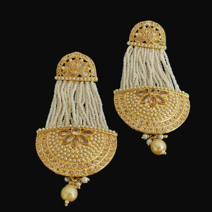 Pair of gold and pearl earrings on a dark background