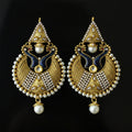A pair of traditional Indian gold-plated earrings with intricate filigree, white faux pearls, and dark blue enamel details, displayed on a dark reflective surface. The Saheli My Best Friend logo is visible in the top left corner.
