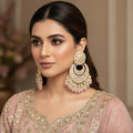 Ornate earrings with pearl and gemstone details on a dark background